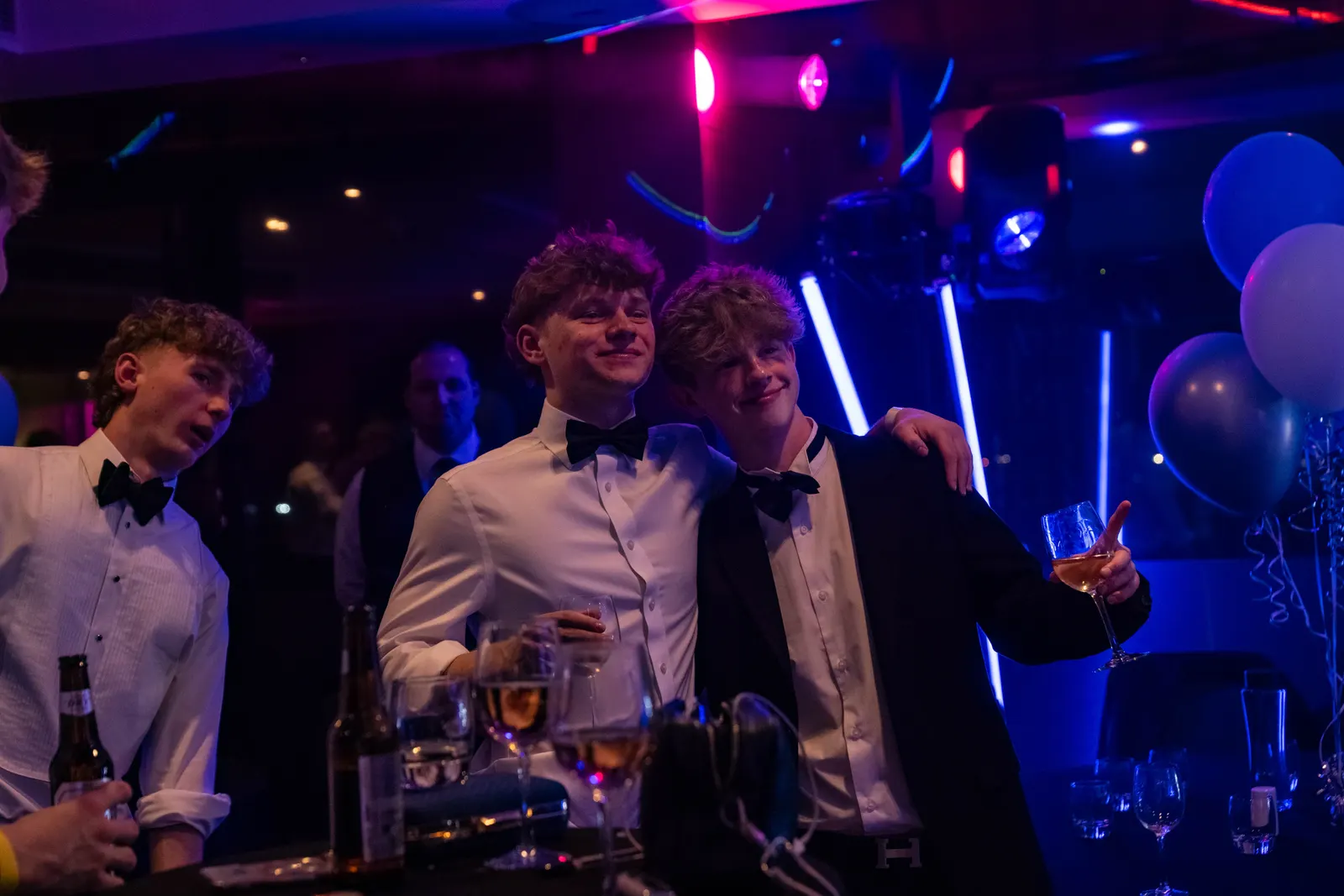 Guests at an 18th birthday party under blue and pink lighting with LED tubes and balloons behind them